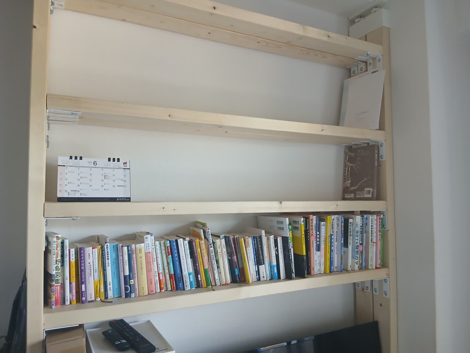テレビの上に自作した2×4の本棚。本がぎっしり並んでいる。