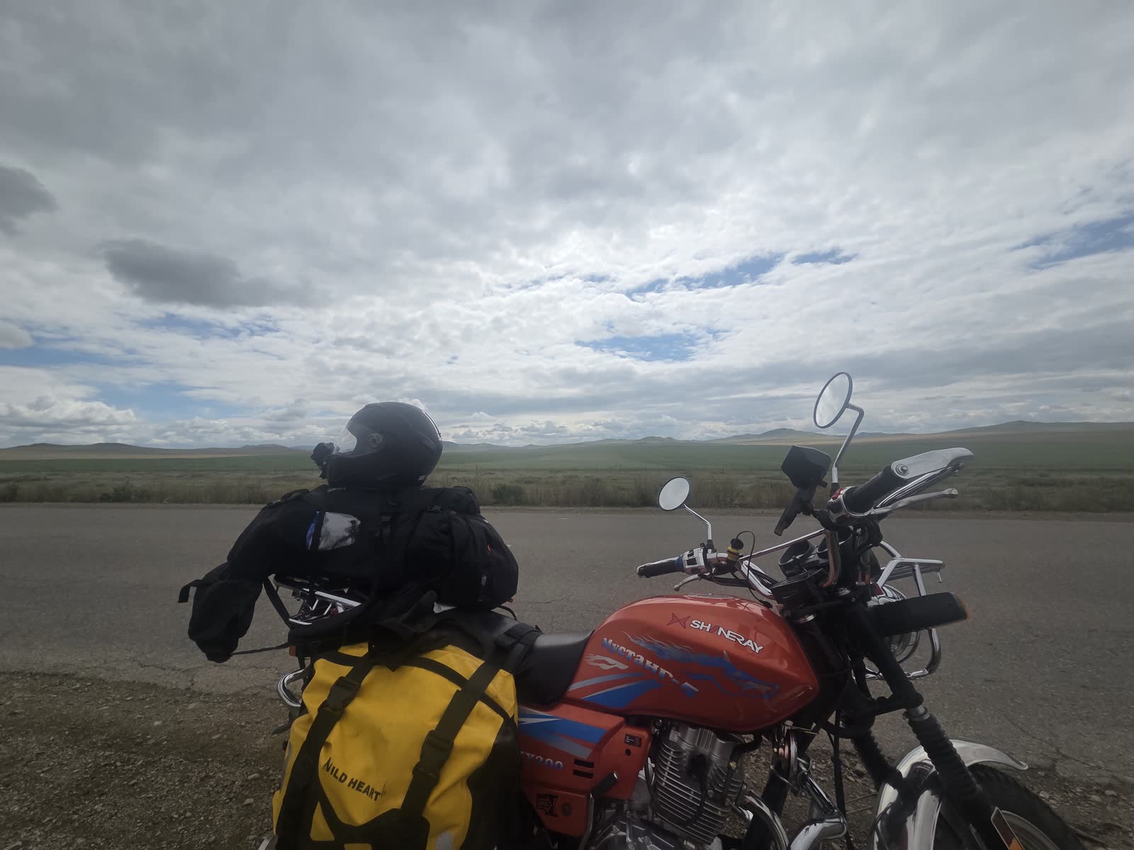 草原の道端に止めたバイクと大きな空