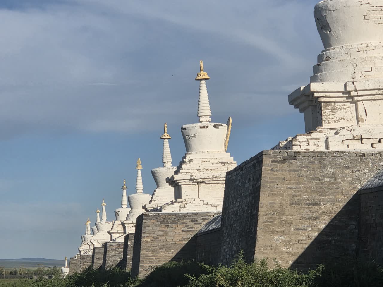 石の外壁の上に並ぶ白い仏塔