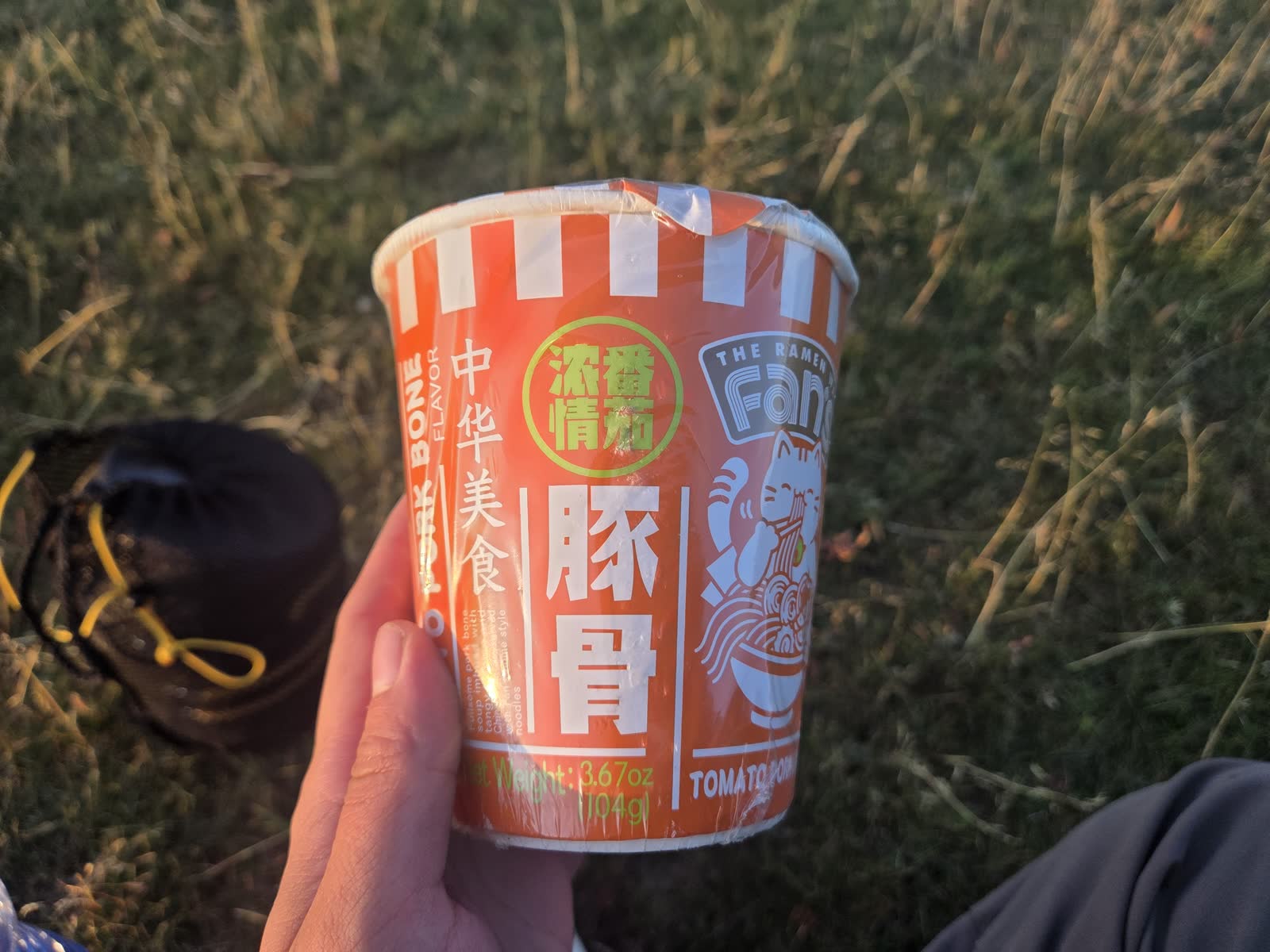 夕日を浴びながら手に持つ、豚骨トマト味のカップ麺